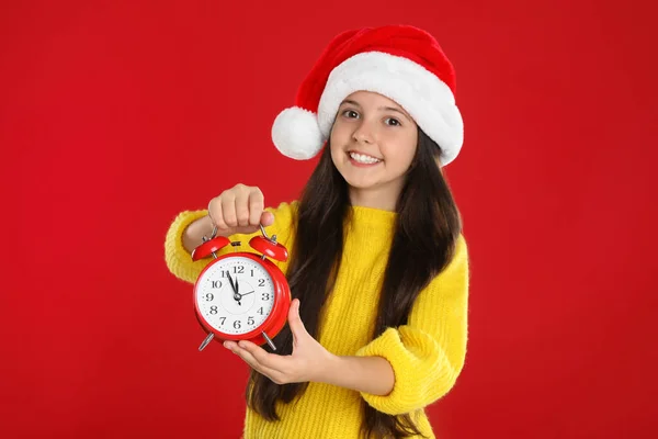 Κορίτσι Σάντα Καπέλο Ξυπνητήρι Στο Κόκκινο Φόντο Χριστουγεννιάτικη Αντίστροφη Μέτρηση — Φωτογραφία Αρχείου