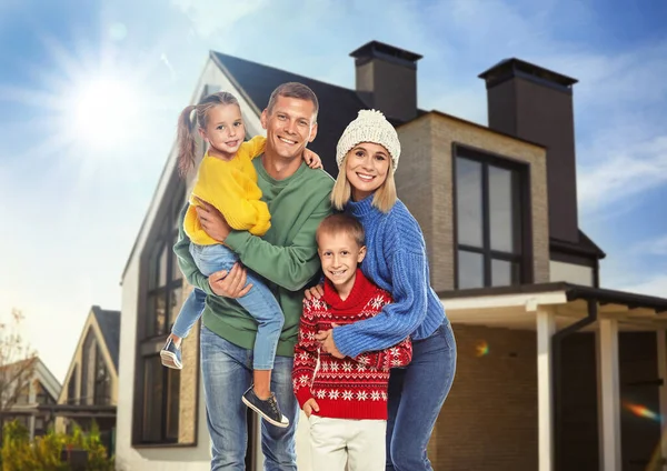 Happy family standing in front of their house on sunny day