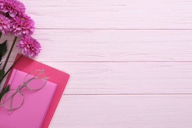Pembe ahşap arka planda güzel çiçekler ve kırtasiye malzemeleri, metin için yeri olan düz bir yer. Öğretmenler Günü