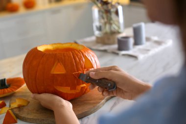 Mutfaktaki masada balkabağı Jack O 'Lantern yapan kadın, yakın plan. Cadılar Bayramı