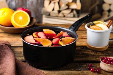 Lezzetli sıcak şarap ve ahşap masadaki malzemeler.