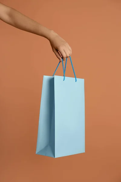 薄い茶色の背景に紙の買い物袋を持っている女性 クローズアップ — ストック写真