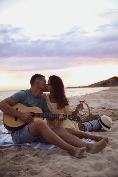 Härligt Par Med Gitarr Och Picknickkorg Stranden Vid Solnedgången — Stockfoto