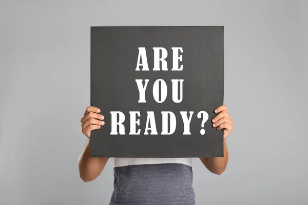 Man holding poster with text Are You Ready? on light grey background