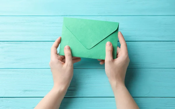 Vrouw Met Groene Papieren Envelop Aan Lichtblauwe Houten Tafel Bovenaanzicht — Stockfoto