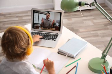 Küçük çocuk evde video konferansı yoluyla öğretmenle ders çalışıyor. COVID-19 salgını sırasında uzaklık öğrenme