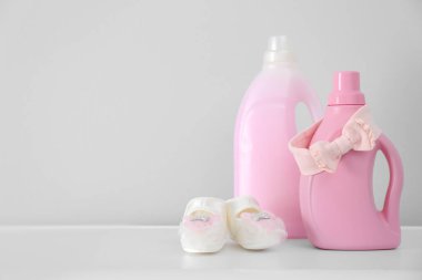 Deterjan şişeleri ve beyaz masada çocuk giysileri. Metin için boşluk