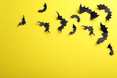 Sarı arkaplanda kağıt yarasalar, metin için boşluk olan düz yataklar. Cadılar Bayramı Dekorasyonu