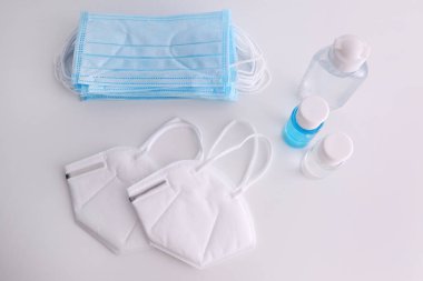 Beyaz arka planda el dezenfektanları ve solunum maskeleri var. COVID-19 salgını sırasında korunması gereken şeyler