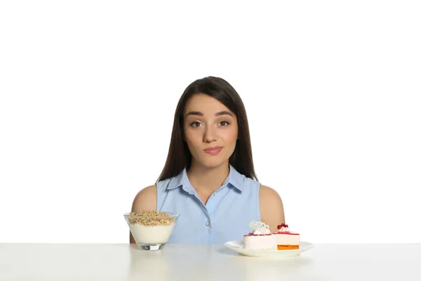 Doubtful Woman Choosing Yogurt Granola Cake Table White Background — Stock Photo, Image