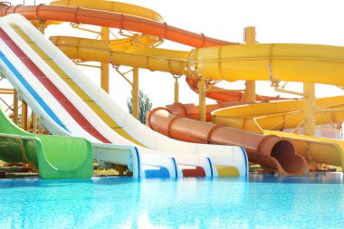 Güneşli bir günde su parkında farklı renkli slaytlar ve yüzme havuzu.
