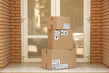 Girişin yanında üzerinde farklı ambalaj sembolleri olan karton kutular. Paket teslimi