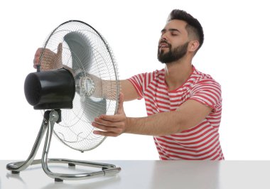 Adam beyaz arka planda vantilatörden hava akımının keyfini çıkarıyor. Yaz sıcağı