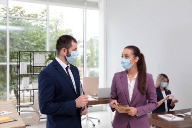 Ofis çalışanları iş yerinde solunum maskesi takıyor.