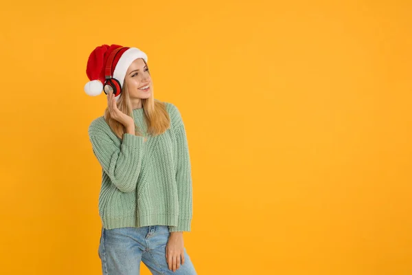 黄色の背景にヘッドフォンを持つ幸せな女性 テキストのためのスペース クリスマス音楽 — ストック写真