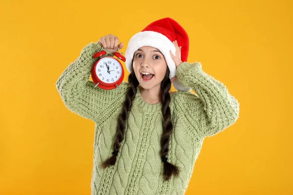Télapó Sapkás Lány Ébresztőórával Sárga Háttérrel Karácsonyi Visszaszámlálás — Stock Fotó