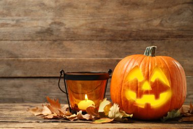 Korkunç balkabağı Jack o 'Lantern ve yanan mum ahşap masada, mesaj için yer var. Cadılar Bayramı Dekorasyonu