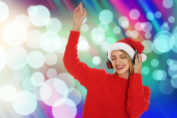 Szczęśliwa Kobieta Kapeluszu Santa Słuchanie Muzyki Świątecznej Słuchawkami Jasnym Tle — Zdjęcie stockowe