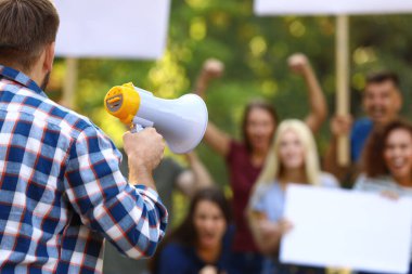 Protesto lideri megafonla dışarıda kalabalıkla konuşuyor.