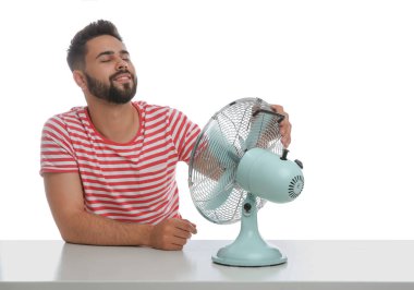 Adam beyaz arka planda vantilatörden hava akımının keyfini çıkarıyor. Yaz sıcağı