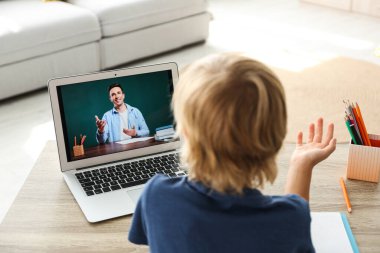 Küçük çocuk evde video konferansı yoluyla öğretmenle ders çalışıyor. COVID-19 salgını sırasında uzaklık öğrenme