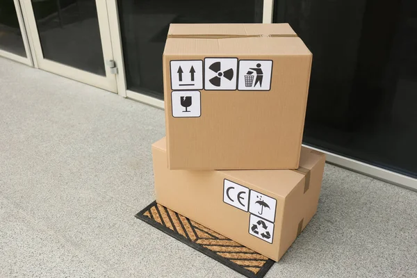 玄関近くのドアマットに異なるパッケージ記号を持つ段ボール箱 小包の配達 — ストック写真