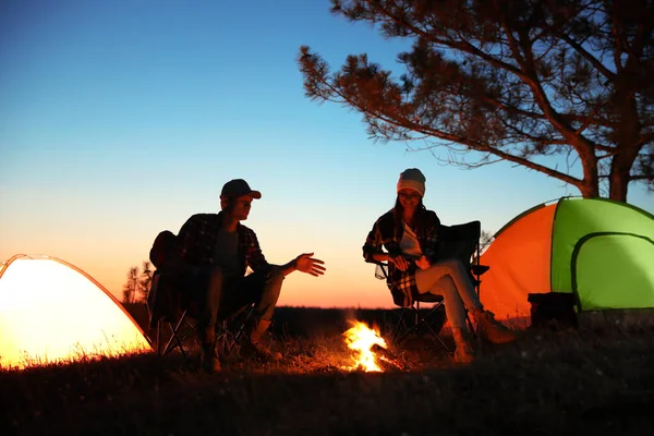 Couple near bonfire in evening. Camping season