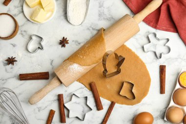 Yuvarlak iğne, hamur, beyaz mermer masa üzerinde noel kurabiyeleri için farklı kesiciler ve malzemeler.