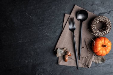 Çatal bıçak takımı, balkabağı ve siyah tahta kaplama arka planda ip, düz yerde yazı için yer var. Tablo ayarlama ögeleri