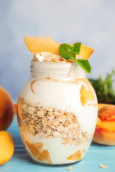 Tasty peach dessert with yogurt and granola on light blue wooden table