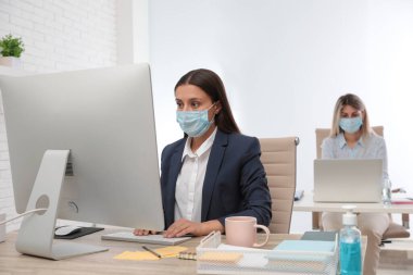 Ofis çalışanları iş yerinde solunum maskesi takıyor.