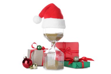 Noel Baba şapkalı kum saati ve beyaz arka planda hediyeler. Noel geri sayımı