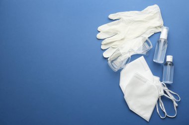 Mavi arka planda tıbbi eldivenler, maskeler ve el dezenfektanı ile düz kompozisyon. Metin için boşluk