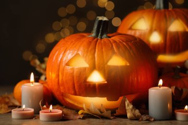 Balkabağı Jack O 'Lantern, sonbahar yaprakları ve arka plandaki bulanık mumlar. Cadılar Bayramı Dekorasyonu