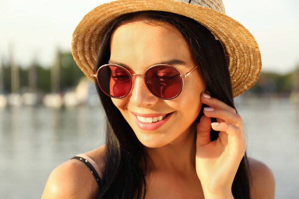 Красивая молодая женщина в стильных солнечных очках возле реки