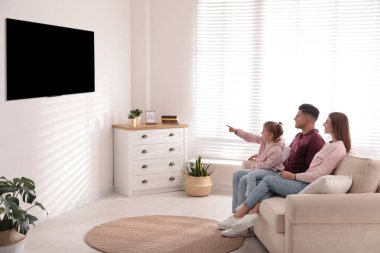 Mutlu bir aile evdeki kanepede televizyon izliyor.