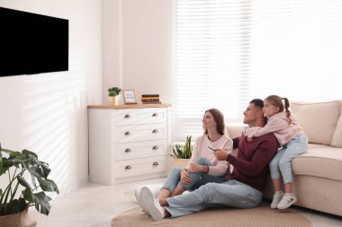 Mutlu bir aile evde yerde televizyon izliyor.