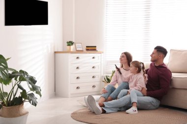 Mutlu bir aile evde yerde televizyon izliyor.