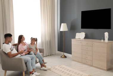 Mutlu bir aile evdeki kanepede televizyon izliyor.