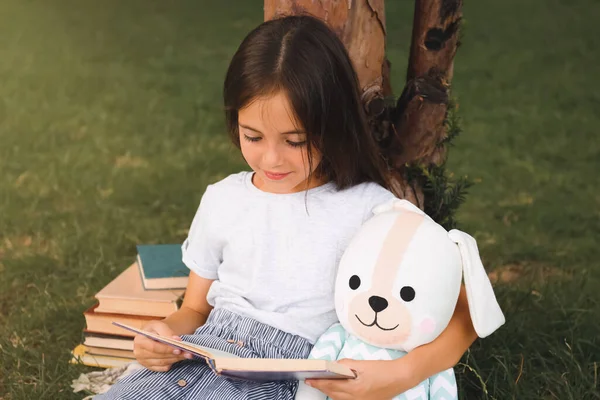 Милая Маленькая Девочка Книжкой Чтения Игрушек Зеленой Траве Рядом Деревом — стоковое фото