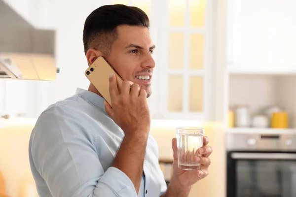 Elinde Bir Bardak Saf Olan Adam Mutfakta Telefonla Konuşuyor — Stok fotoğraf