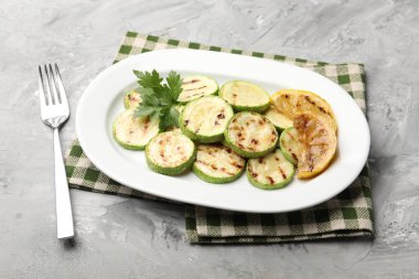 Gri masada servis edilen limonlu ve maydanozlu lezzetli kabak dilimleri.