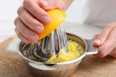 Meyve suyu. İçerideki masada meyve sıkacağı kullanan portakallı kadın, yakın plan.