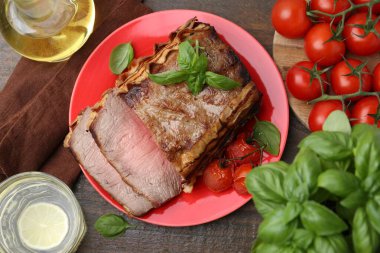 Lezzetli pişmiş et, domates, fesleğen ve ferahlatıcı içecek ahşap masada, düz yatıyordu.