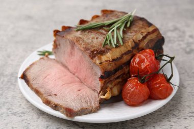 Lezzetli pişmiş et, domates ve biberiye gri masada, yakın plan.