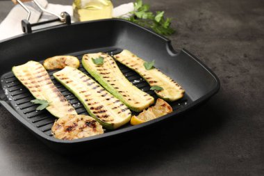 Gri masadaki tavada sarımsak, limon ve maydanozlu lezzetli kabak dilimleri, yakın plan.