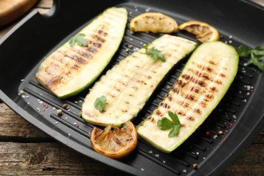 Baharatlı lezzetli ızgara kabak dilimleri ve ahşap masada limon, yakın plan.