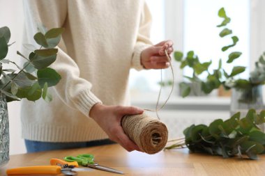 Çiçekçi dükkanındaki ahşap masada güzel okaliptüs dalları yapan bir makara ipliği olan çiçekçi.