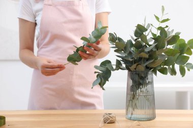 Çiçekçinin ahşap masasında okaliptüs dallarından güzel bir buket yapıyor.