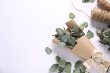 Çiçekçi. Okaliptüs dalları ve iplikler beyaz masada, düz yerde. Metin için boşluk